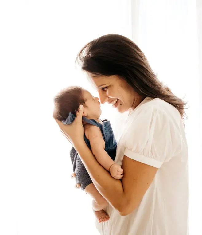 Ouderschapsverlof 2022. Een vrouw heeft een baby vast en lacht heel hard.