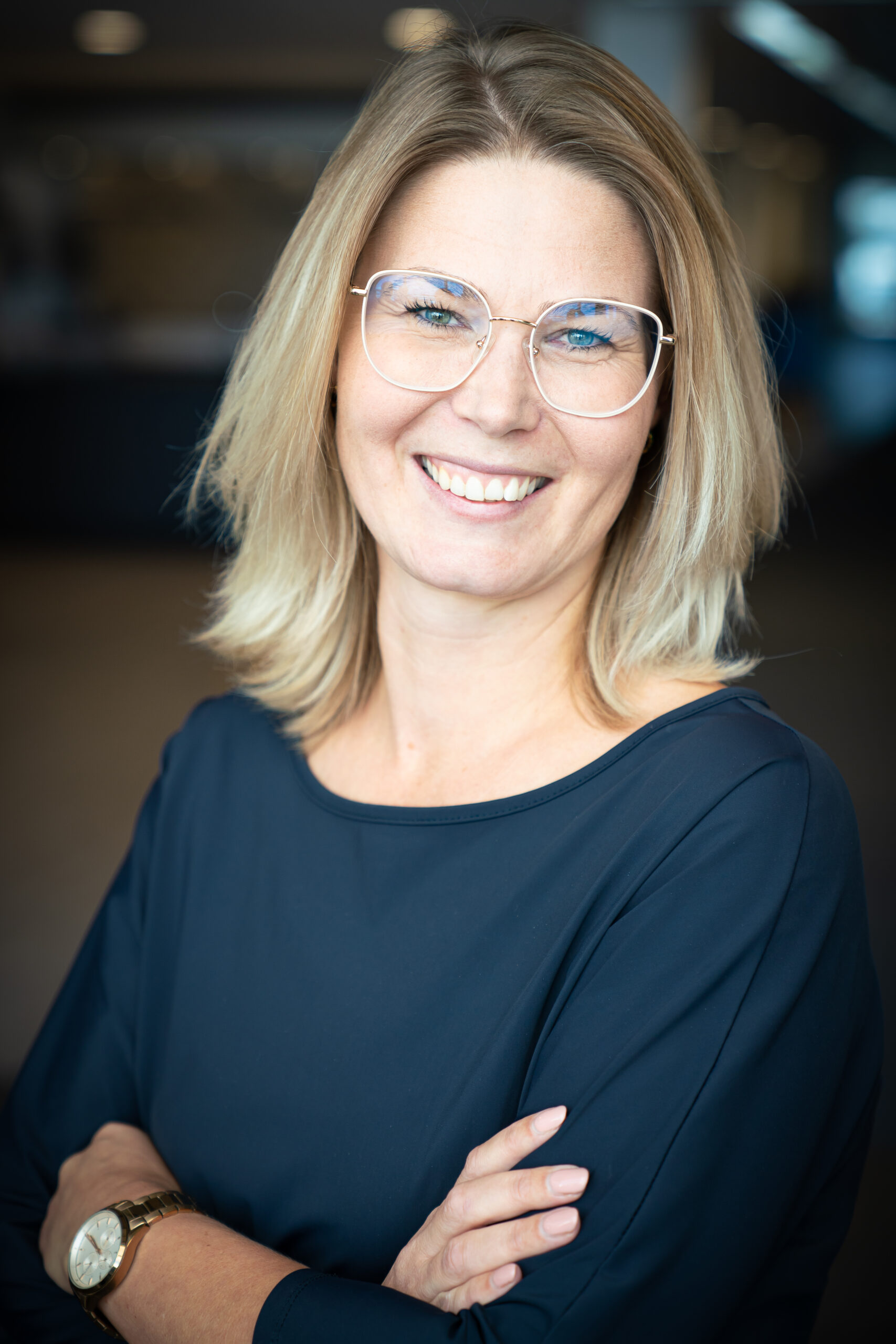 Glimlachende vrouw die met haar armen over elkaar recht in de camera kijkt