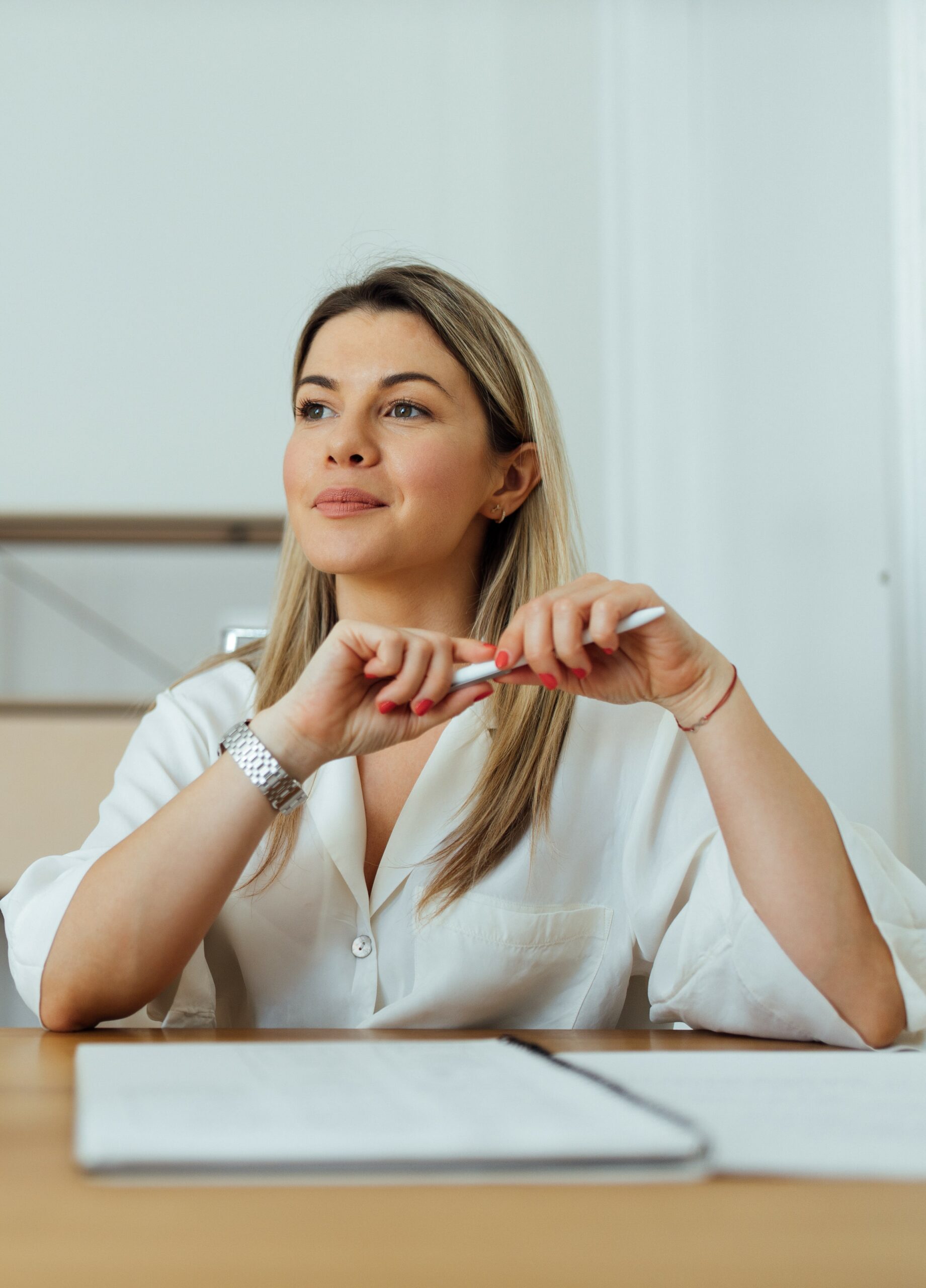 Blonde vrouw aan een bureau met een pen die zich inleest over de ketenbepaling staande foto