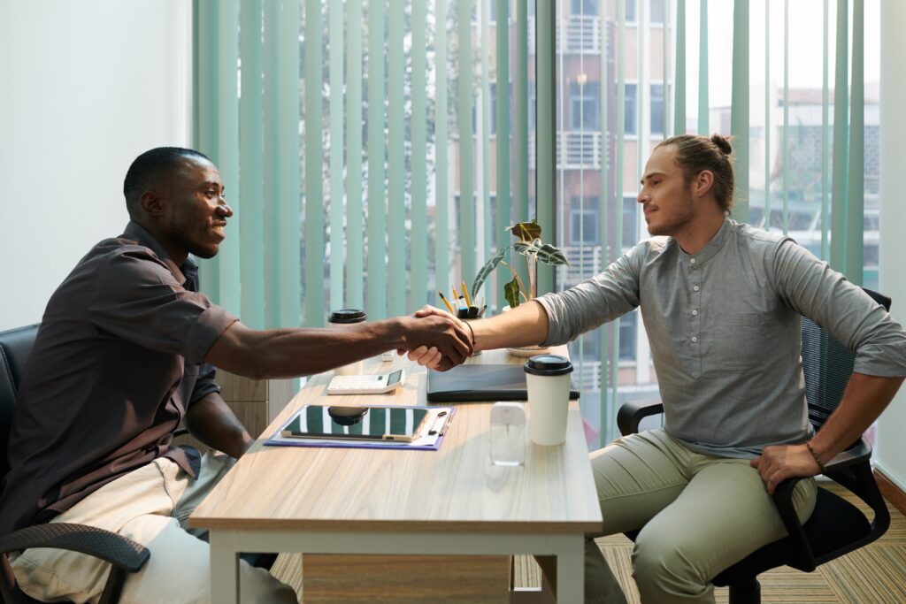 Recruiter schudt handen met en sollicitant die hij heeft aangenomen op basis van zijn competenties